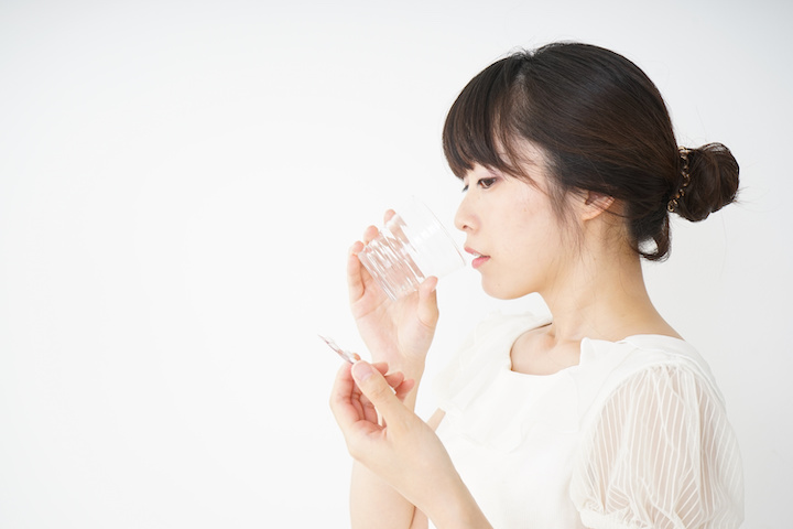痛み止めを飲む女性