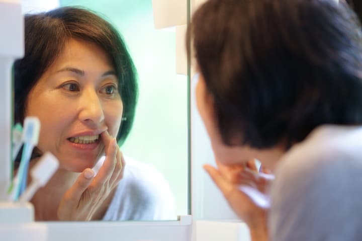 歯茎が大丈夫か気になって鏡でチェックする女性