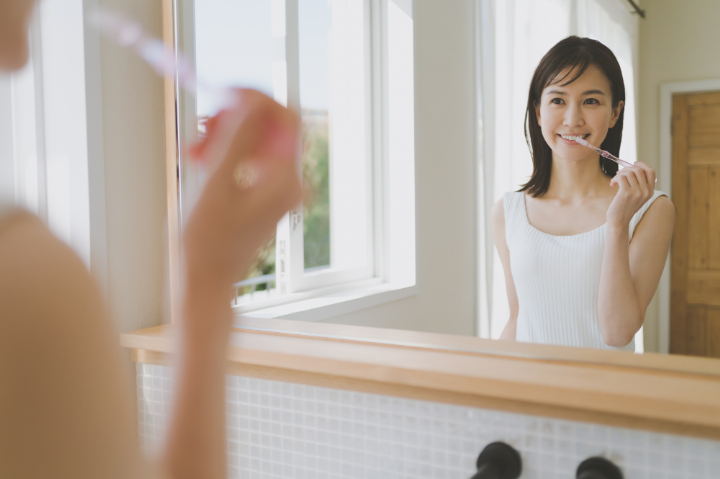 鏡を見ながら丁寧に歯磨きする女性