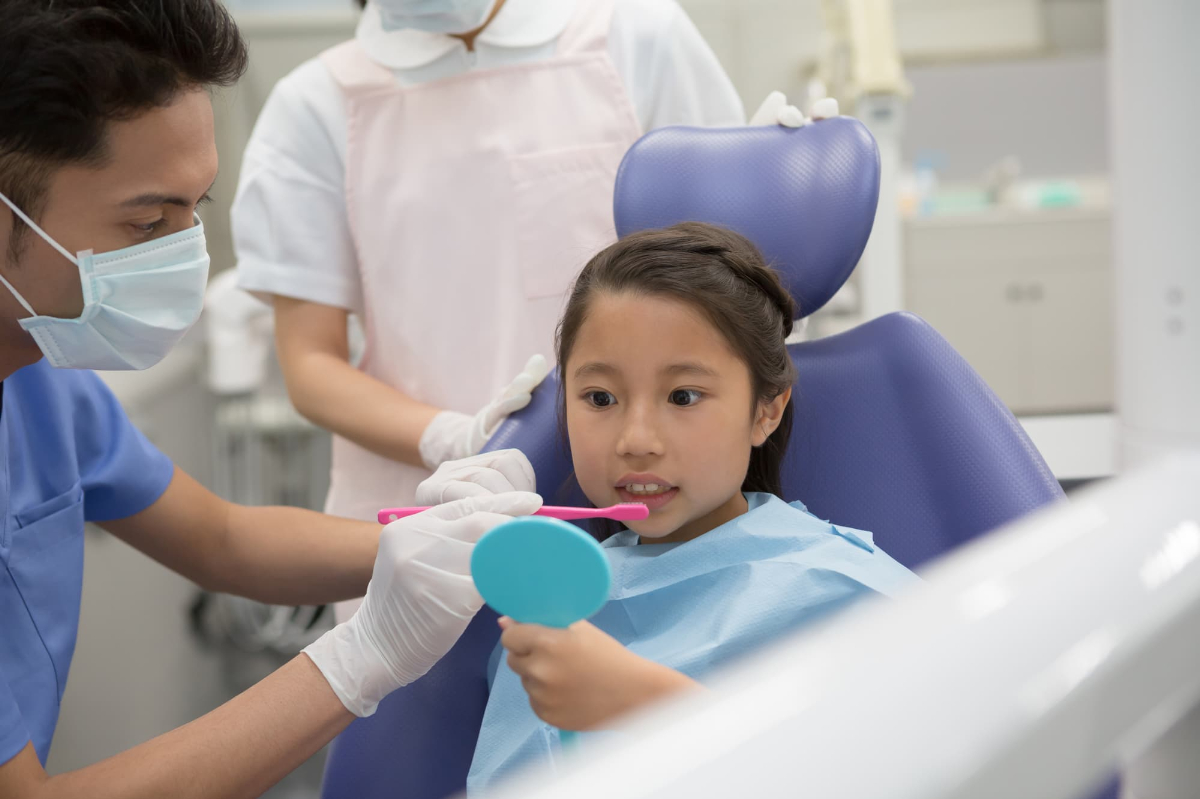 口臭予防に歯科医にブラッシング指導を受ける子ども