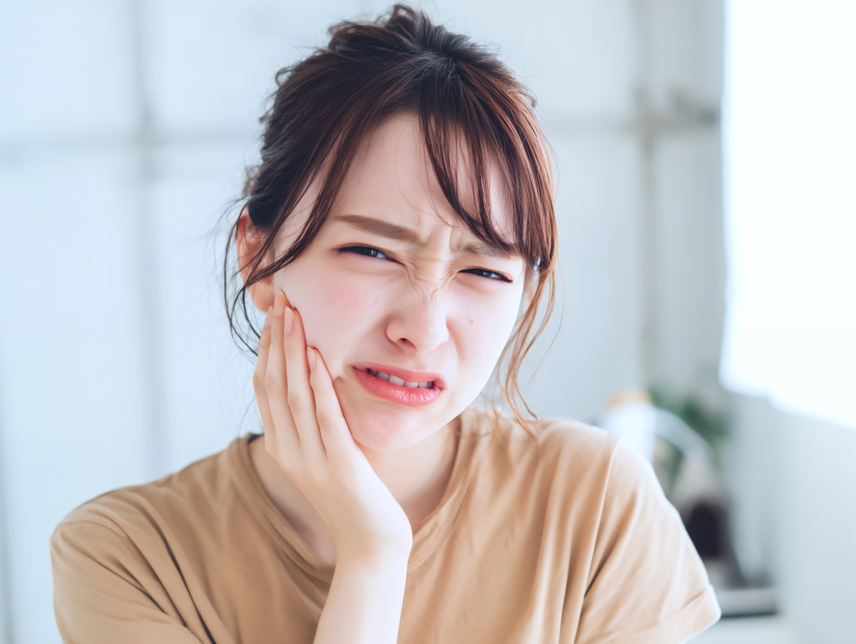 インプラント治療での歯の痛みに顔をしかめる若い女性